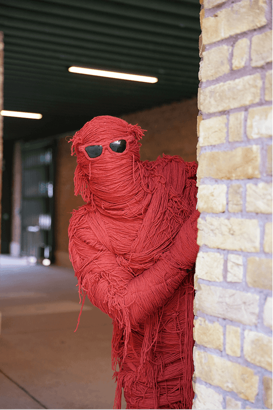 Fred peering around a brick corner at MAD//Fest 2026