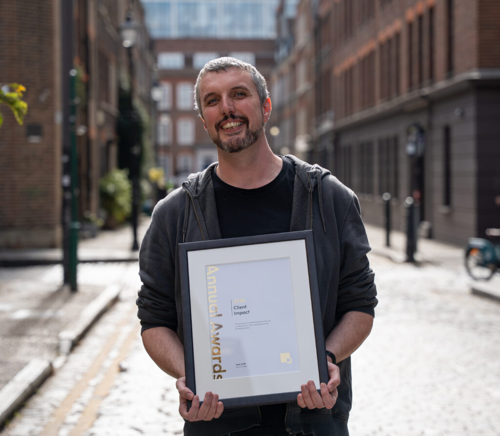 Duncan Brown in a London street holding his award certificate