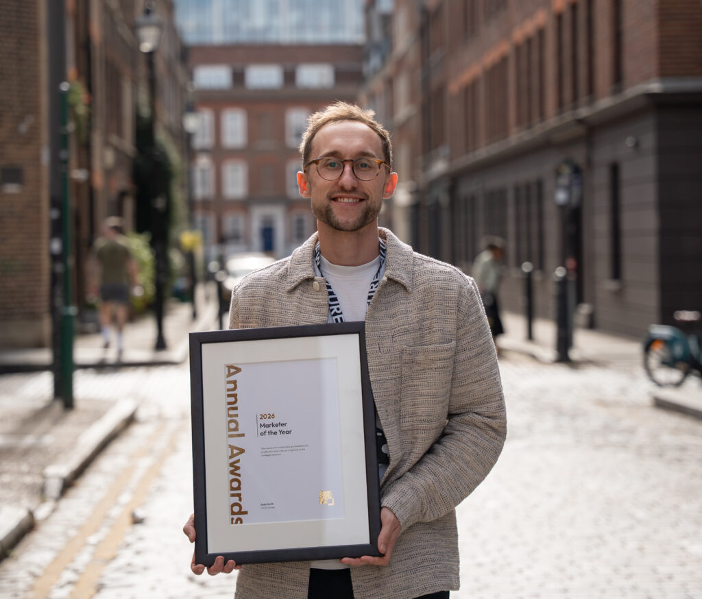 Max Buch standing in a London side street holding his award certificate