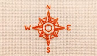 A compass stitched in red thread
