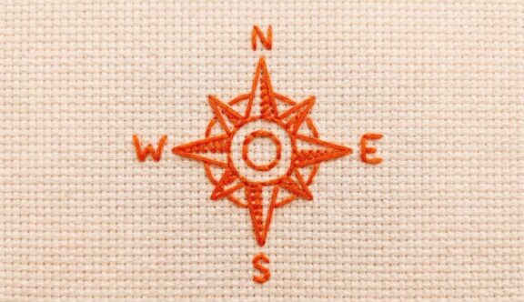 A compass stitched in red thread